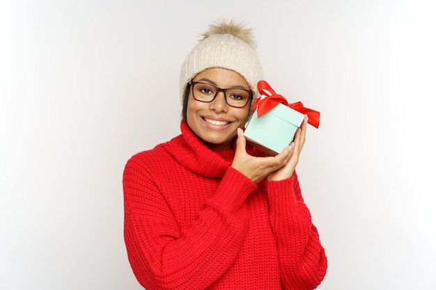 Mujer feliz con sombrero de invierno mantenga regalo de Navidad sonriente mujer afroamericana celebrando el año nuevo