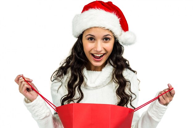 Mujer feliz con sombrero de Navidad abriendo bolso de compras rojo