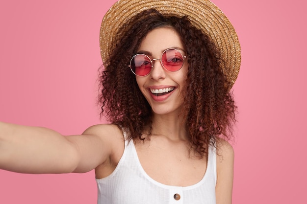 Mujer feliz con sombrero de paja tomando selfie