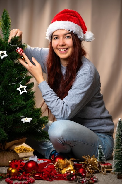 Foto mujer feliz con sombrero de santa decora el árbol de año nuevo