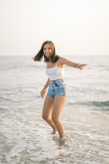 Mujer feliz sonriendo en la orilla de la playa