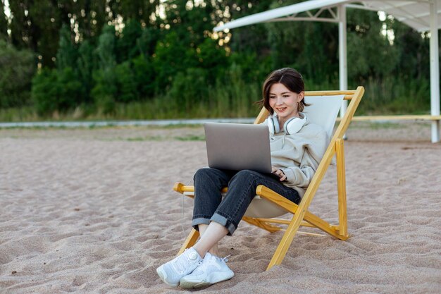 Mujer feliz sonriendo trabajando en una laptop en una playa