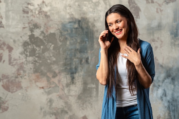 Mujer feliz sonriente que habla en el smartphone contra un fondo abstracto.