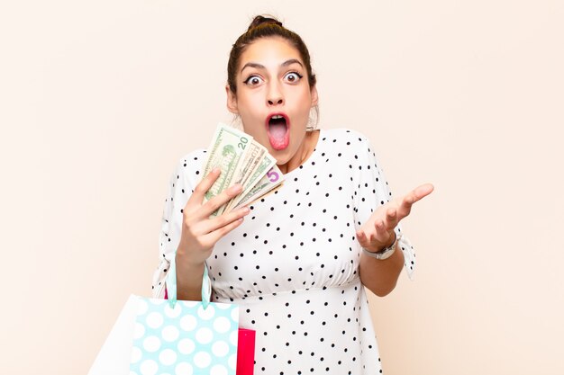 Mujer feliz sorprendida con dinero y bolsas de compras