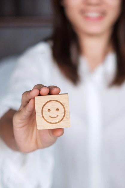 Mujer feliz sosteniendo el bloque de la cara de la emoción de la sonrisa El cliente elige Emoticon para las reseñas de los usuarios Calificación del servicio Salud mental Pensamiento positivo Evaluación de satisfacción y concepto de retroalimentación