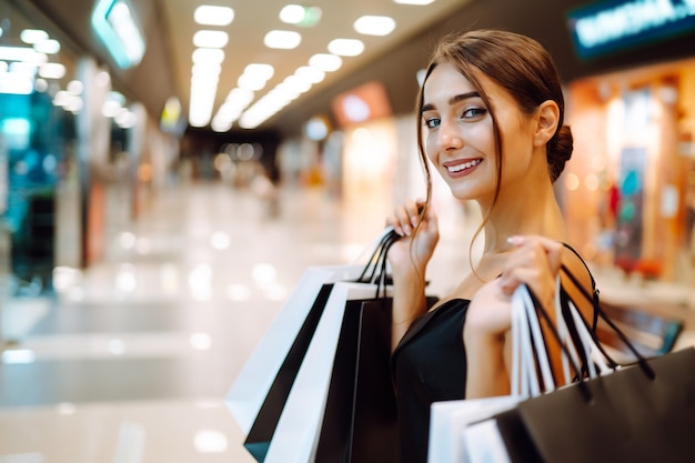 Mujer feliz sosteniendo bolsas de la compra y sonriendo en el centro comercial