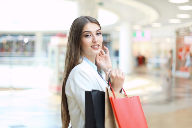 Mujer feliz sosteniendo bolsas de la compra y sonriendo en el centro comercial.