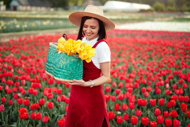 Mujer feliz sosteniendo cesta con tulipanes en ámbito rural