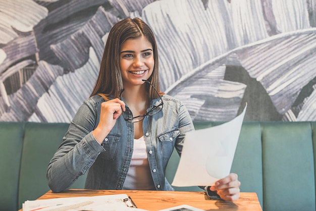 Foto la mujer feliz sosteniendo un papel en la mesa de un café