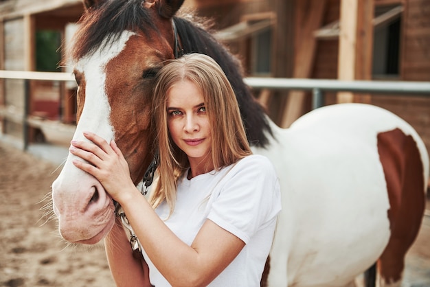 Mujer feliz con su caballo en el rancho durante el día.