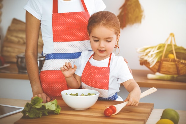 Una mujer feliz y su hija están buscando nuevas recetas para una cocina soleada que festeja en familia