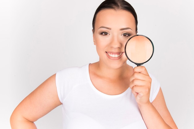 mujer feliz con su piel limpia y sana, concepto de belleza de feminidad de cuidado de la piel. mujer sosteniendo lupa en su cara.