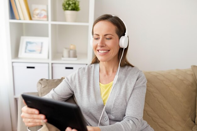 mujer feliz con tablet PC y auriculares en casa