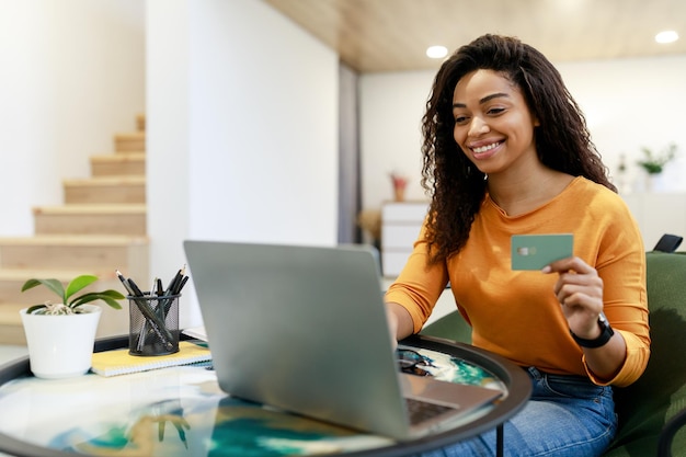 Mujer feliz con tarjeta de crédito de débito usando pc