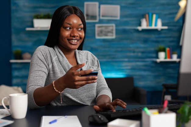 Mujer feliz con tarjeta de crédito para hacer compras en línea en la computadora y sonriendo. Persona que se siente emocionada por comprar ropa en el sitio web, utilizando dinero bancario para realizar compras en Internet