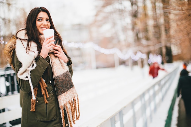 Mujer feliz con una taza de bebida caliente en invierno al aire libre en el mercado de Navidad