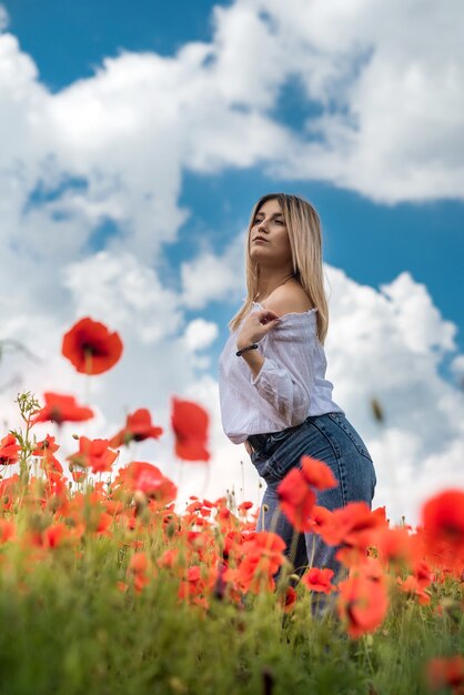 Mujer feliz en tela casual en el campo de amapolas disfruta de tiempo de verano gratis