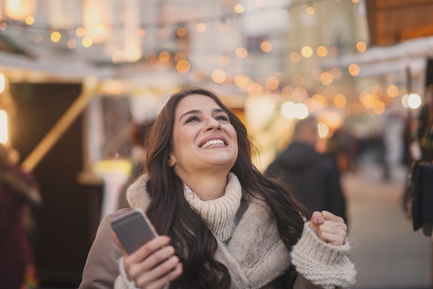 Mujer feliz con teléfono inteligente al aire libre.