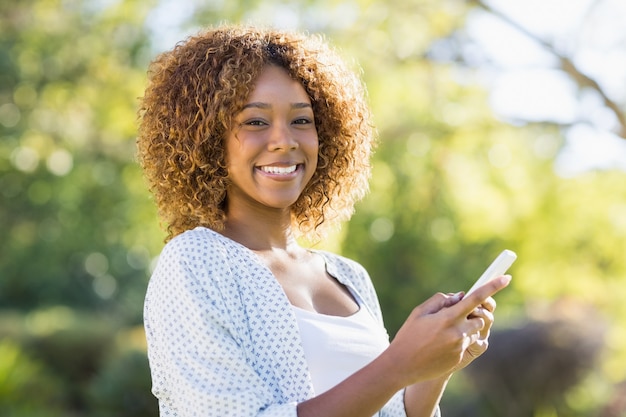 Mujer feliz con teléfono móvil en el parque