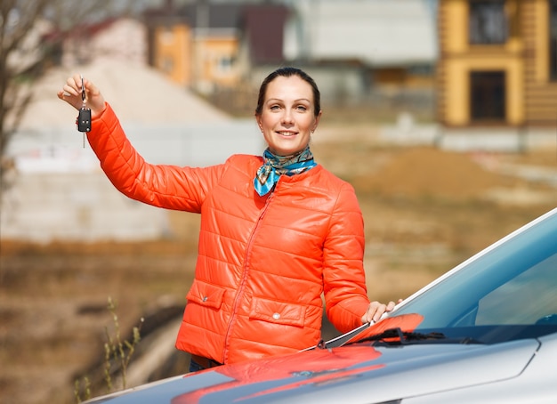 Mujer feliz tiene las llaves del fondo de la casa del coche