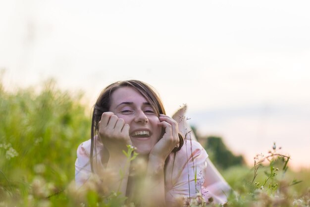 Foto mujer feliz tirada en el prado por la noche