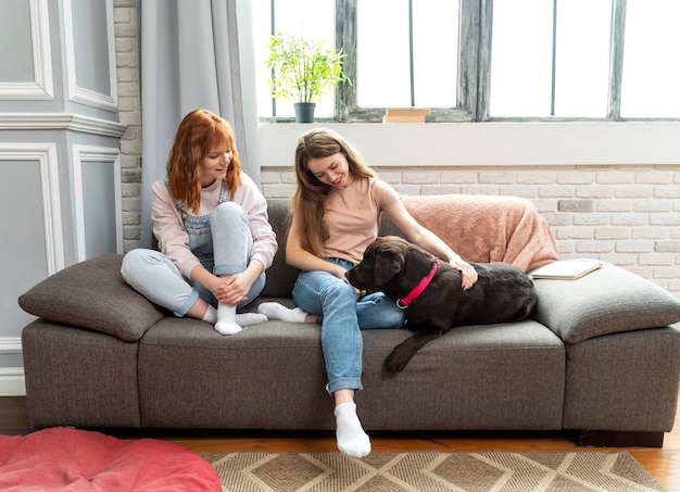 Foto mujer feliz de tiro completo y perro en el sofá