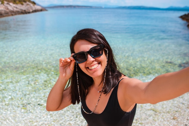 Mujer feliz tomando selfie en la playa del mar
