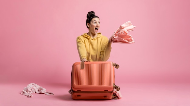 Foto mujer feliz tomando su ropa de un equipaje