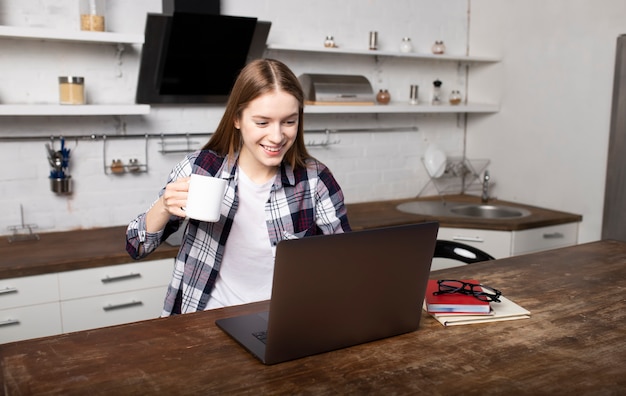 Mujer feliz trabajando en casa por la mañana. La niña bosteza. Ella esta usando su laptop