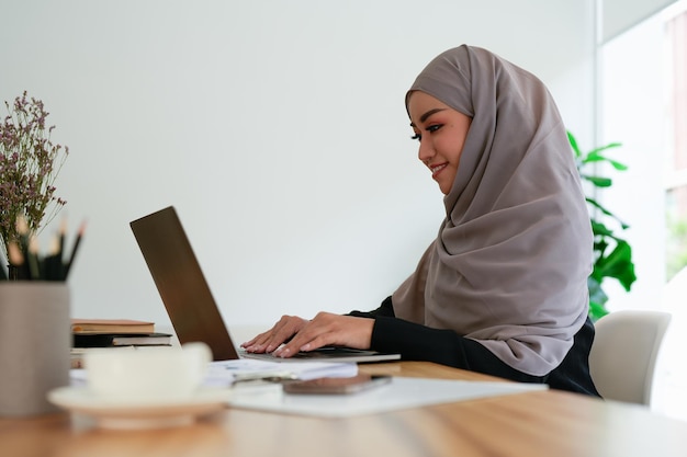 Mujer feliz trabajando en una computadora portátil en la oficina