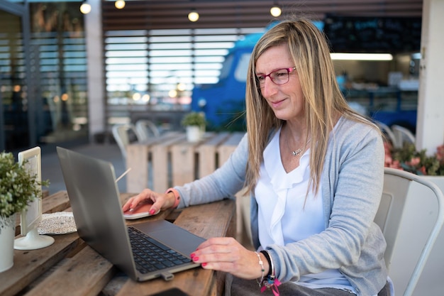 Mujer feliz trabajando con su laptop en una cafetería