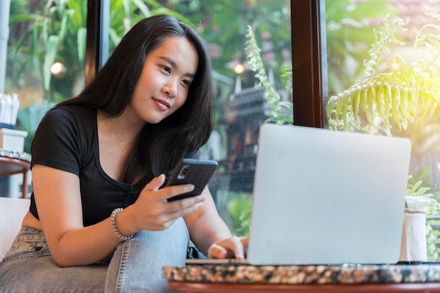 Mujer feliz trabajando usando múltiples dispositivos en un escritorio en una cafetería