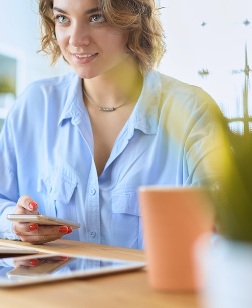 Mujer feliz trabajando usando múltiples dispositivos en un escritorio en casa