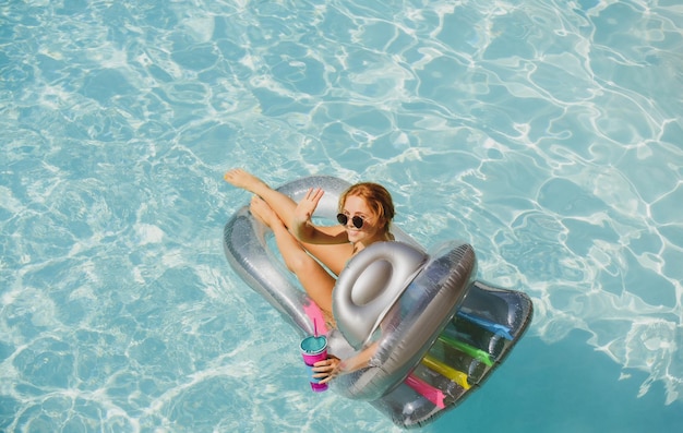 Mujer feliz en traje de baño chica en vacaciones de verano mujer en piscina sobre colchón inflable