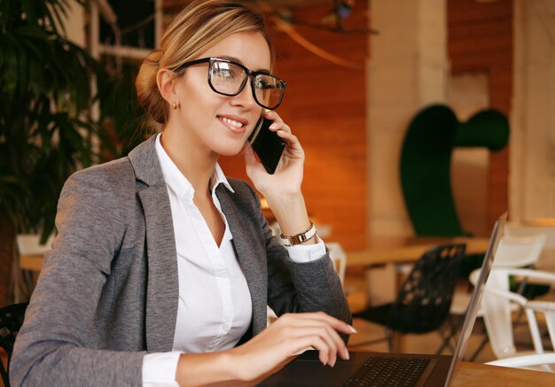 Mujer feliz usando chat con móvil y usando computadora portátil