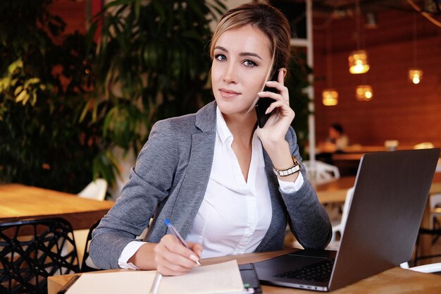 Mujer feliz usando chat con móvil y usando computadora portátil