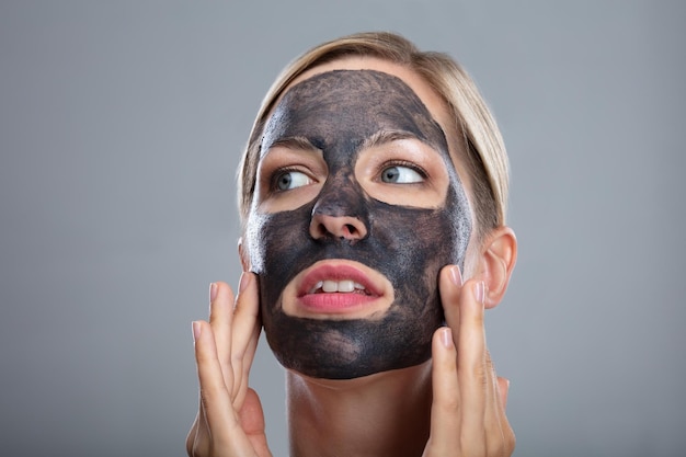 Mujer feliz usando mascarilla de carbón activado