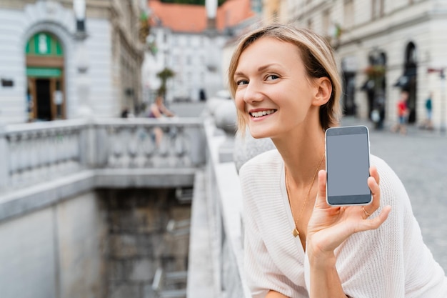 Mujer feliz usando teléfono inteligente en la calle de una ciudad europea Estilo de vida moderno de la gente urbana