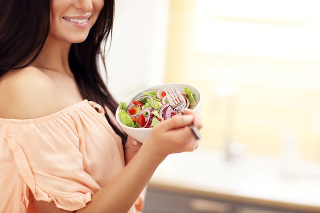 Mujer feliz con verduras en la cocina moderna