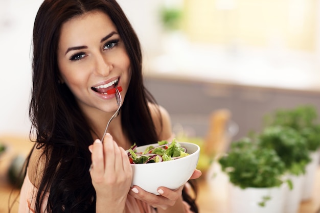 Mujer feliz con verduras en la cocina moderna