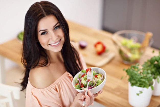 Mujer feliz con verduras en la cocina moderna