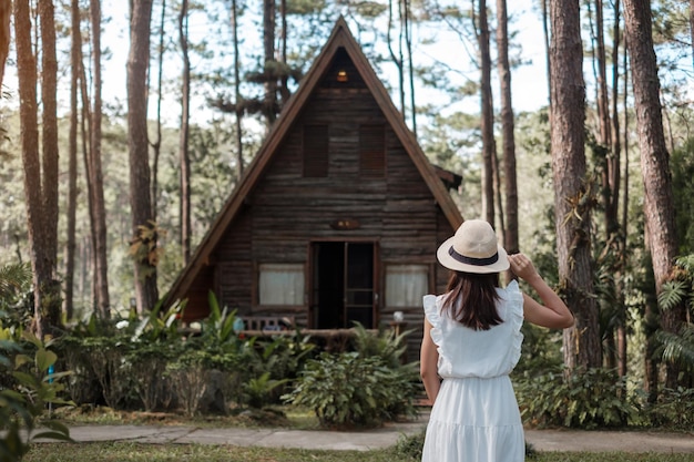 Foto mujer feliz con vestido blanco y sombrero que viaja en una visita turística al bosque de pinos en doi bo luang chiang mai tailandia punto de referencia y popular para las atracciones turísticas concepto de vacaciones y viajes