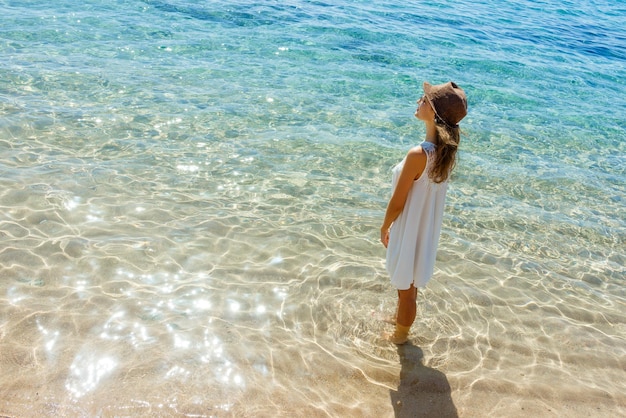 Mujer feliz con vestido blanco de verano en la chica de la playa relajándose y disfrutando de la paz en vacaciones