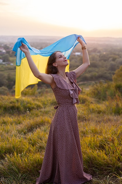 Mujer feliz con vestido largo sosteniendo una bandera amarilla y azul de Ucrania