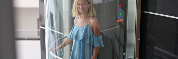 Foto mujer feliz en vestido paseos en un ascensor de cristal