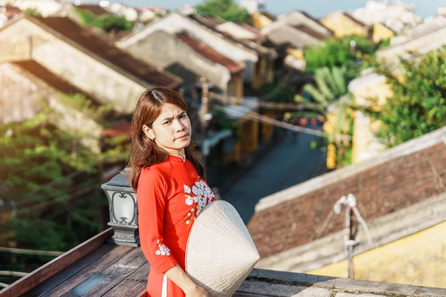 Mujer feliz con un vestido vietnamita de Ao Dai, vista turística en la azotea de la antigua ciudad de Hoi An en Vietnam, punto de referencia y popular para las atracciones turísticas Concepto de viaje de Vietnam y el sudeste
