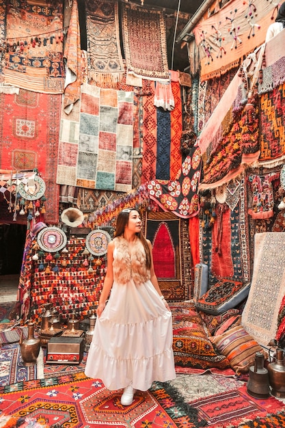 Mujer feliz viaje con increíbles alfombras de colores en la tienda de alfombras locales, Goreme. Capadocia Turquía