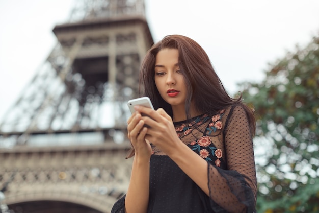 Mujer feliz viaje con smartphone cerca de la torre Eiffel y el carrusel, París. Retrato de viaje