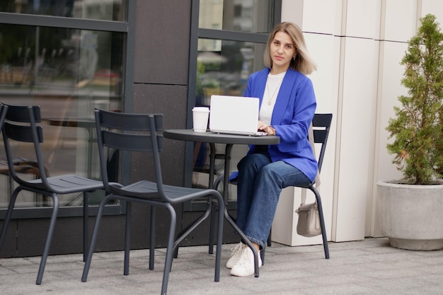 Mujer feliz viendo contenido de medios en línea en una computadora portátil sentada en un parque