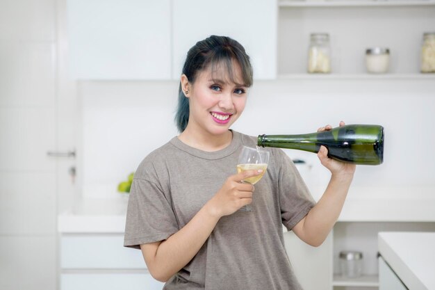 Una mujer feliz vierte champán en un vaso.